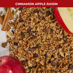Detail shot of Cinnamon Apple Raisin granola texture showing apple pieces, raisins, and cinnamon sticks with label 'Cinnamon Apple Raisin'