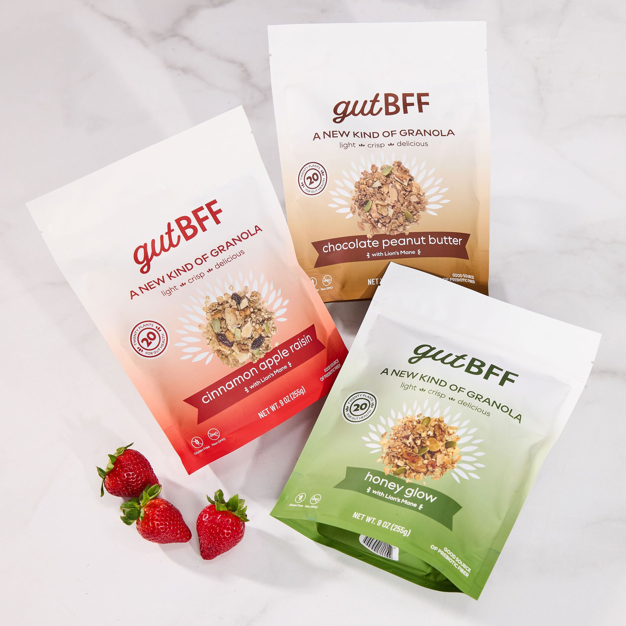 Three delicious varieties of gutBFF flavors in Honey Glow, Cinnamon Apple Raisin, and Chocolate Peanut Butter packages on a light background with strawberries.