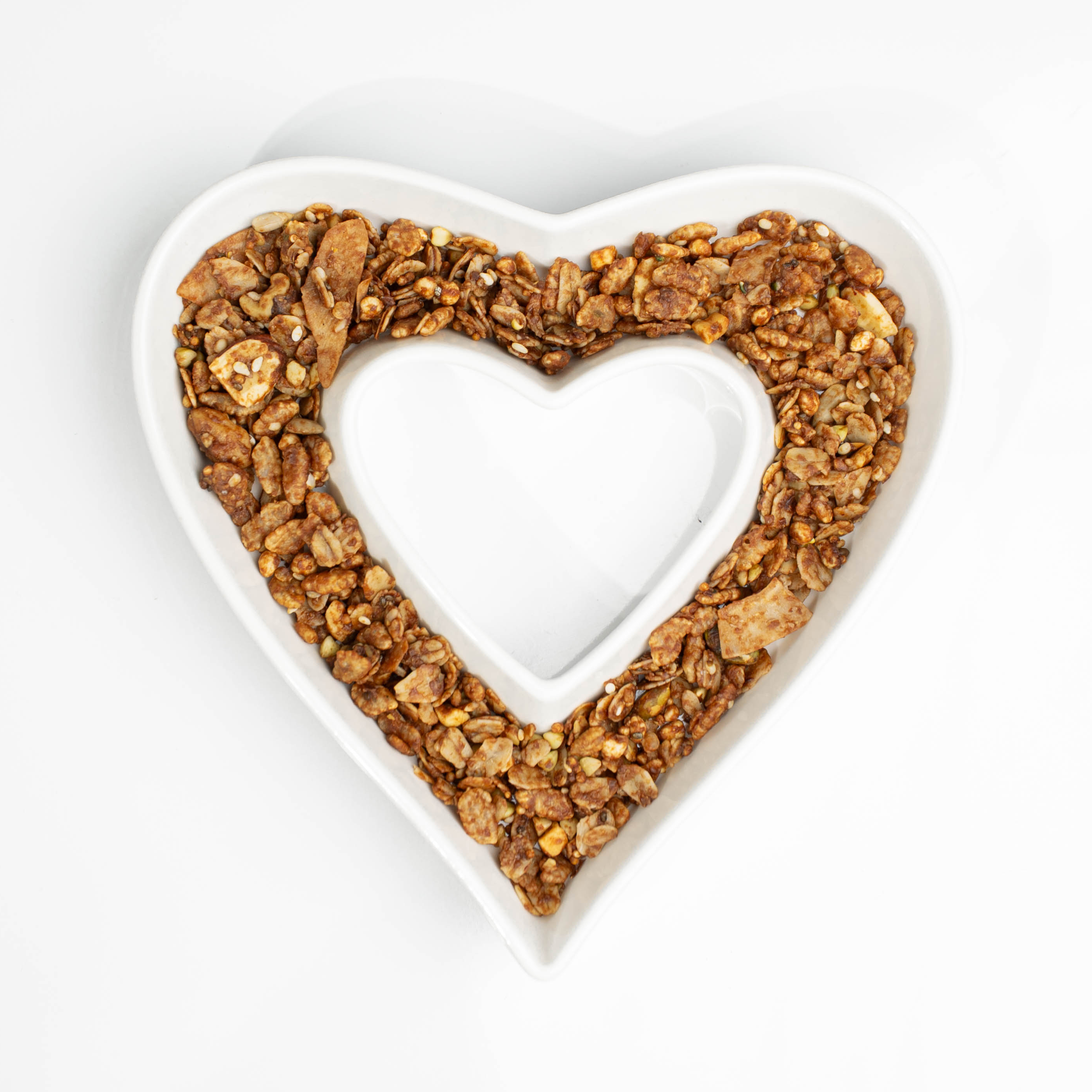 Heart-shaped dish filled with gutBFF granola on a white background
