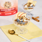 Warm Cinnamon Apple Raisin granola, formulated for gut health served with fresh fruit and yogurt in a glass bowl on a yellow napkin with a spoon.
