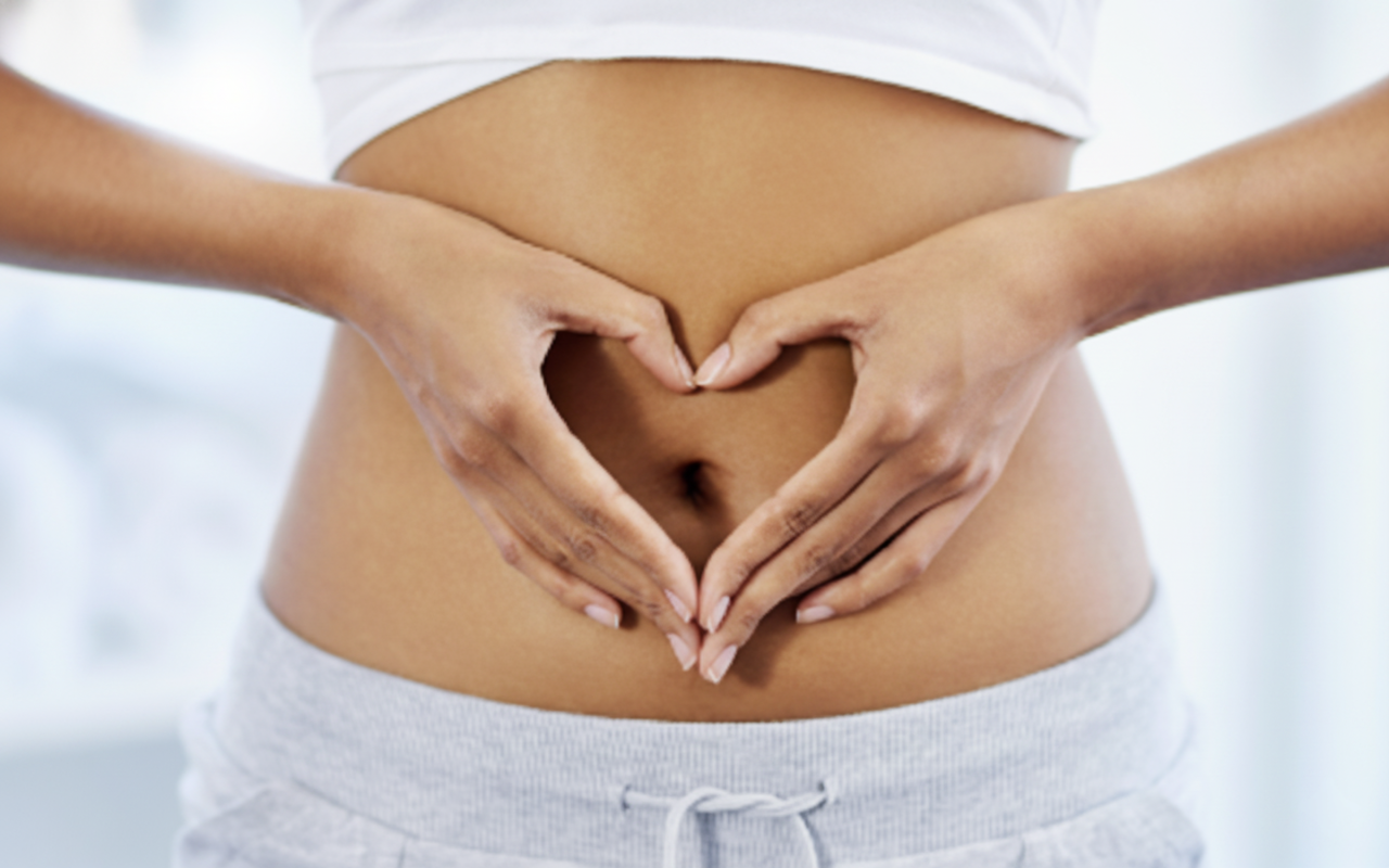 Person forming a heart shape with their hands over their stomach